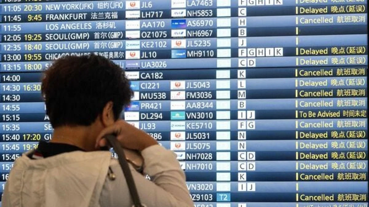 Traveler at an airport departure board showing delayed and cancelled flights including Chicago O'Hare during severe weather disruption